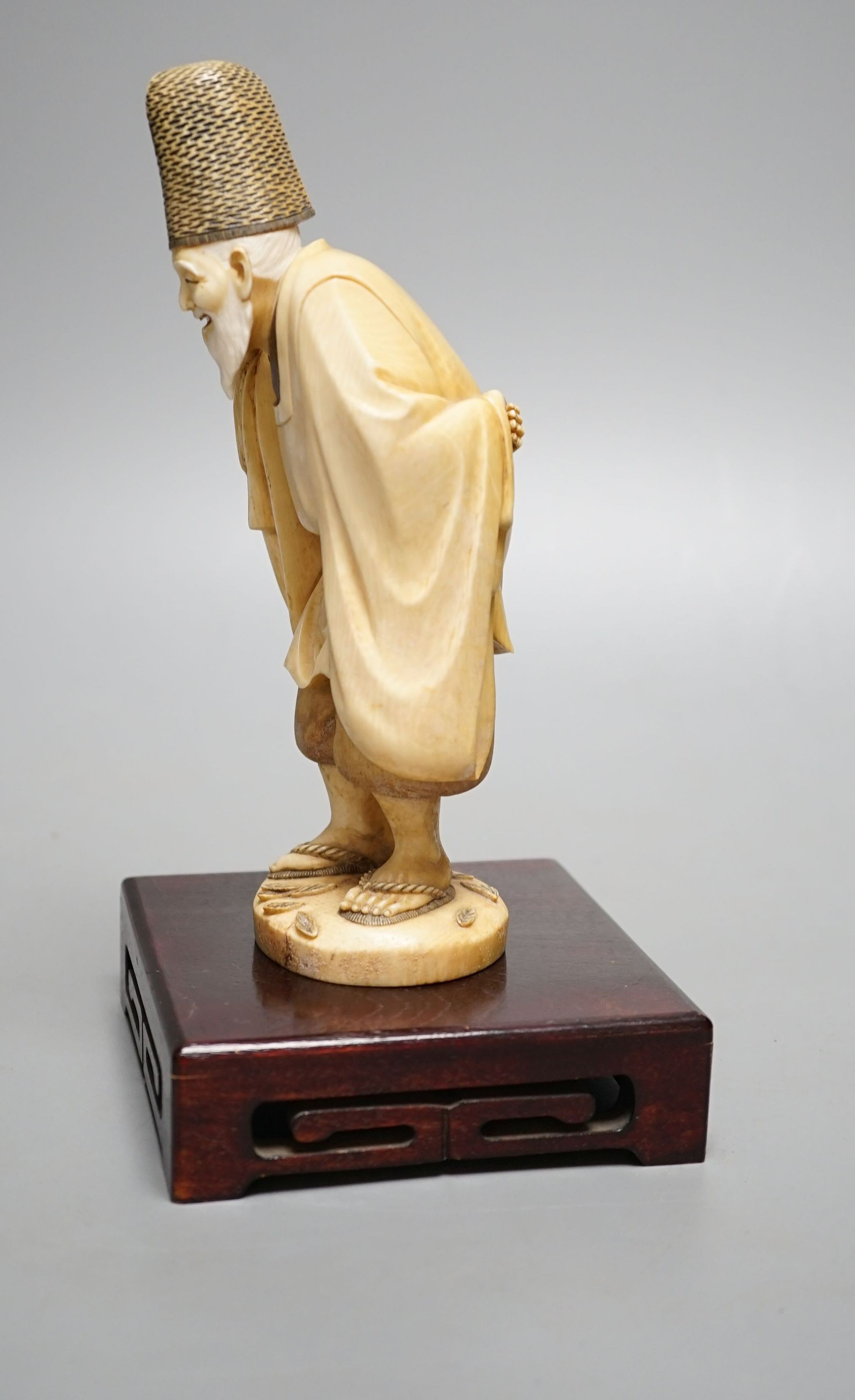 A Japanese ivory figure of a court official, wearing a tall eboshi hat, Taisho period, signed to a lacquer tablet - 18.5cm tall